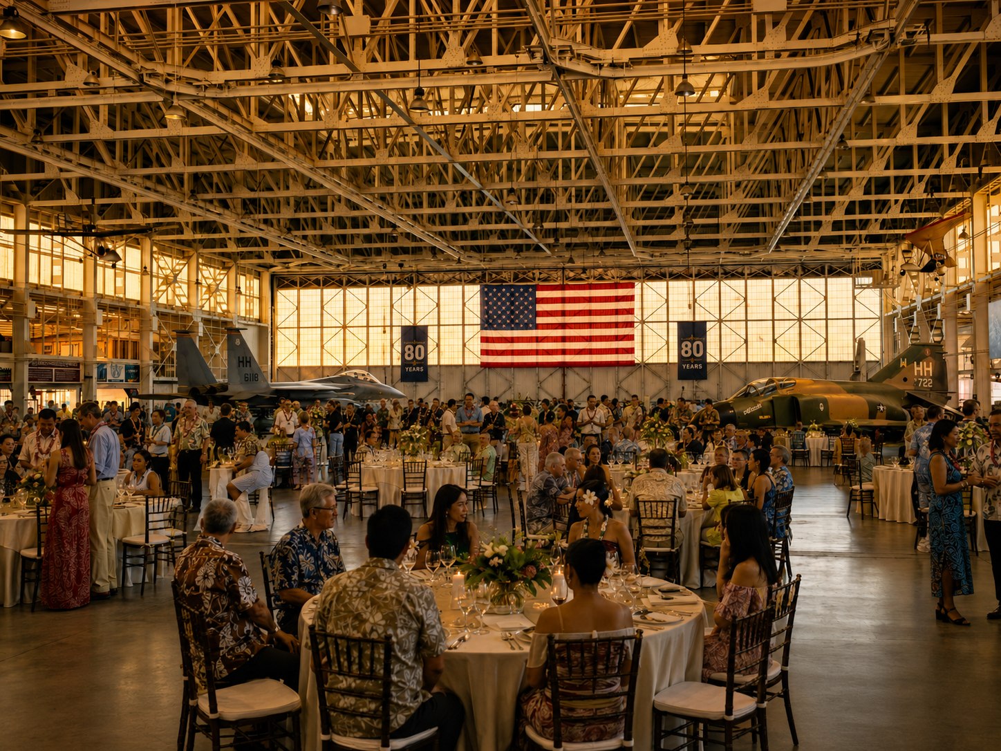 Concept view of the HIANG 80th anniversary celebration filling Hangar 79 with round dinner tables, guests in aloha attire, and historic aircraft